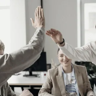 Professional colleagues giving high-fives in an office setting